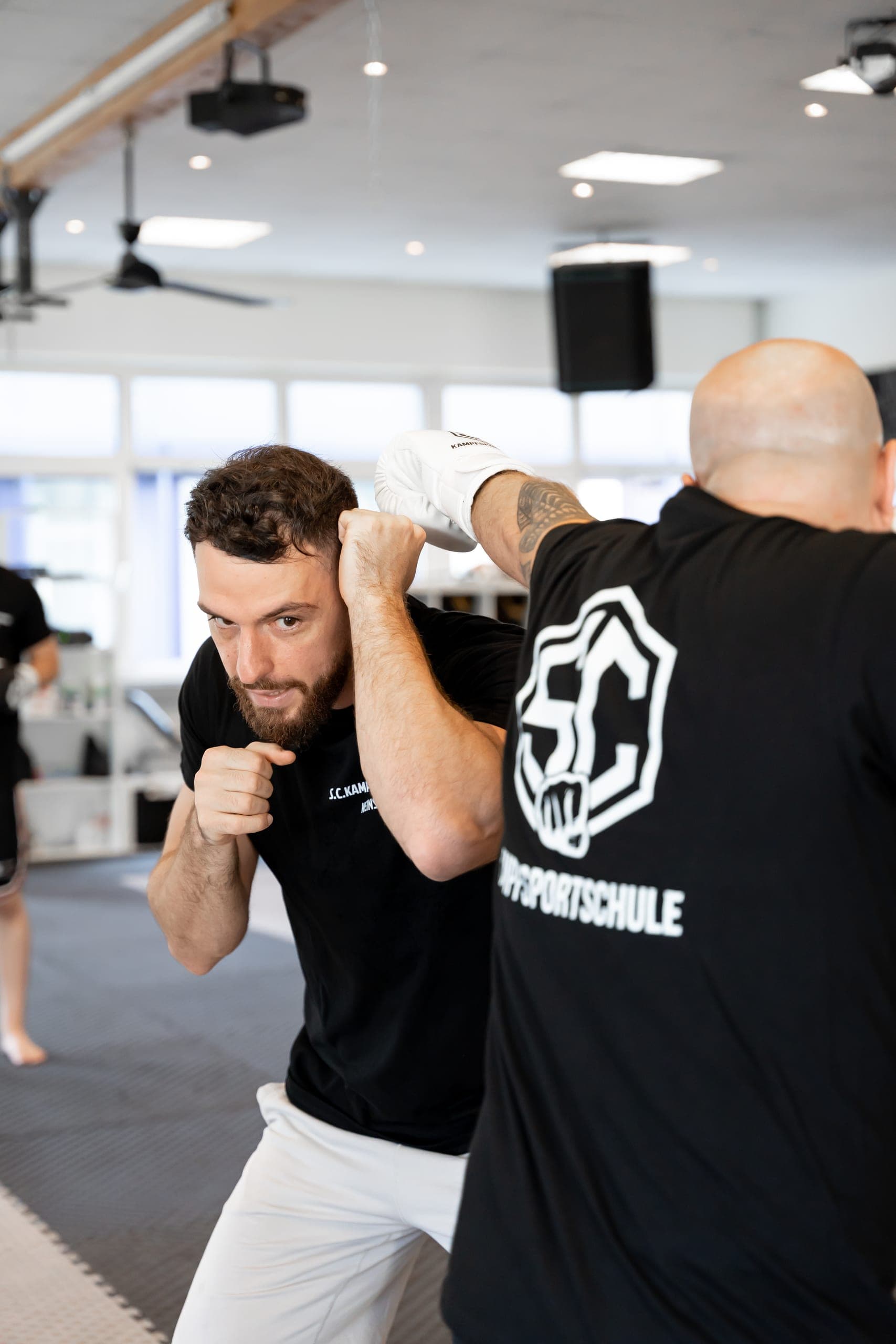 Erwachsener in der Deckung beim Boxtraining, der Partner schlägt zur Pratze